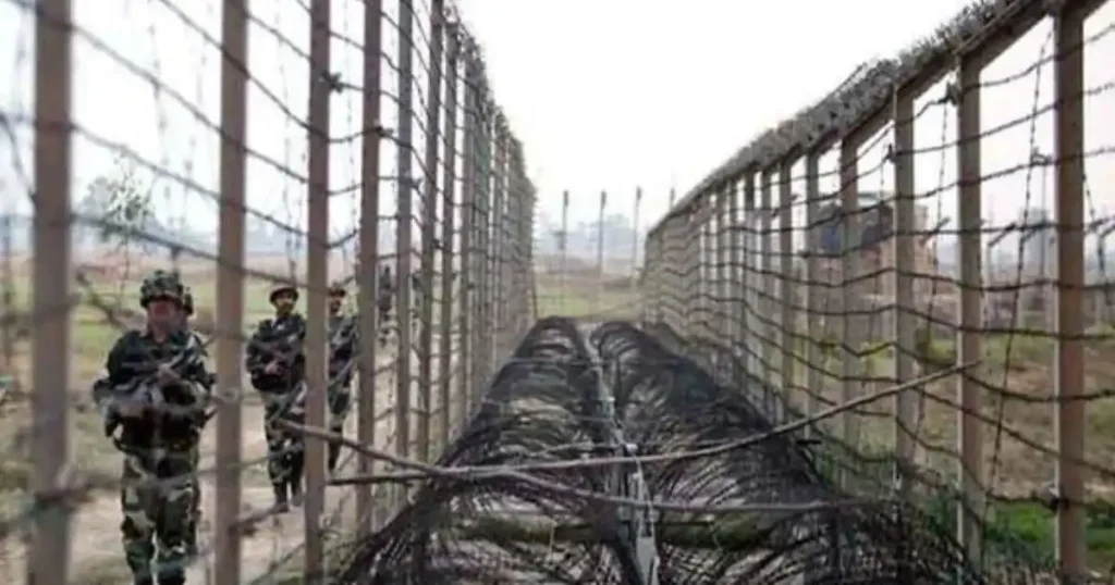 India Bangladesh border fencing area with BSF personnel patrolling near barbed wire security barrier in West Bengal
